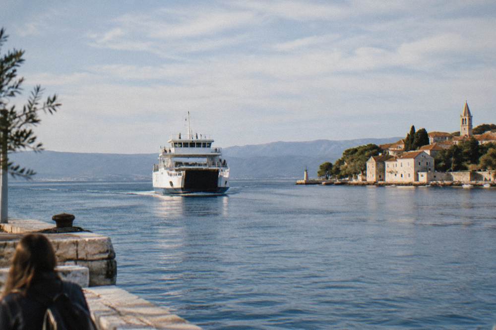 A car ferry approaching an island port on a calm blue Adriatic morning