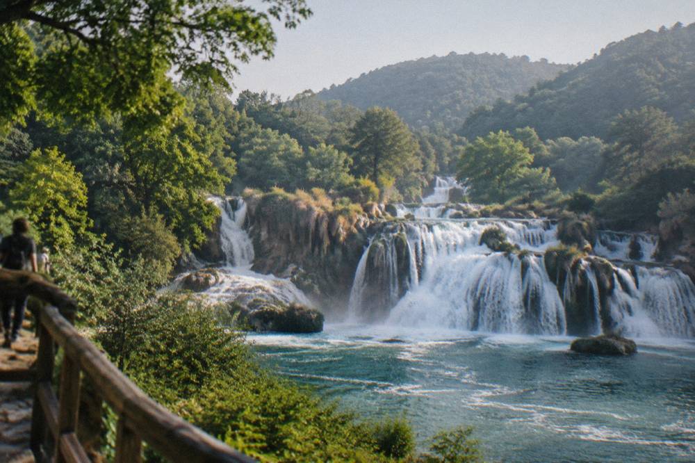 Waterfalls spilling over travertine barriers in a green river canyon national park