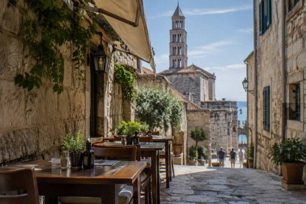 A konoba terrace with wooden tables in a narrow stone street in Split