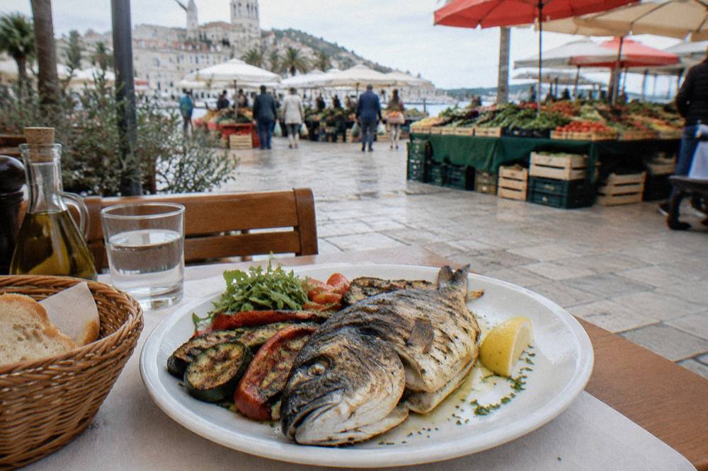 A plate of grilled fish and vegetables on a restaurant table