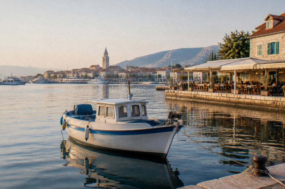 A boat moored at an island port with a waterside restaurant behind it