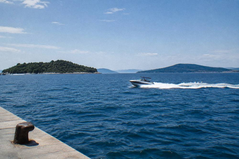 A speedboat cutting across open sea between islands near Split