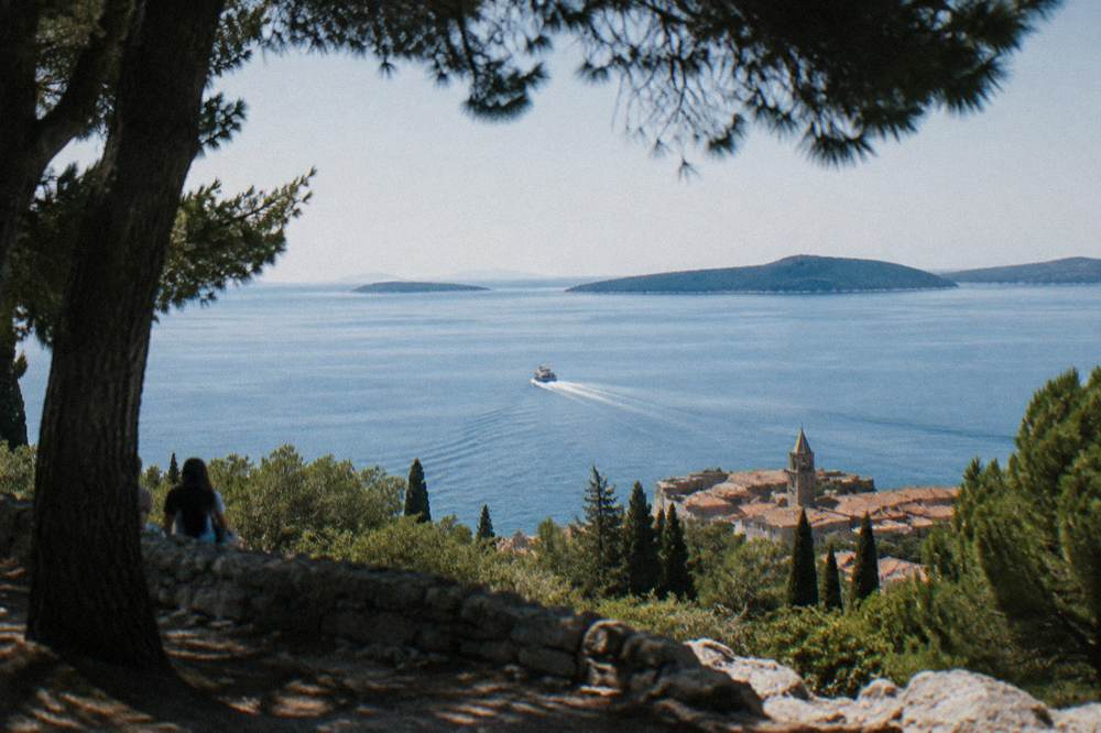A small boat crossing calm blue water towards islands at the end of the afternoon