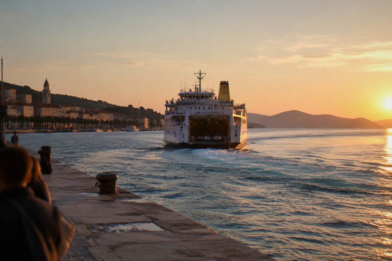 A car ferry leaving Split harbour with the Adriatic sea and island hills on the horizon