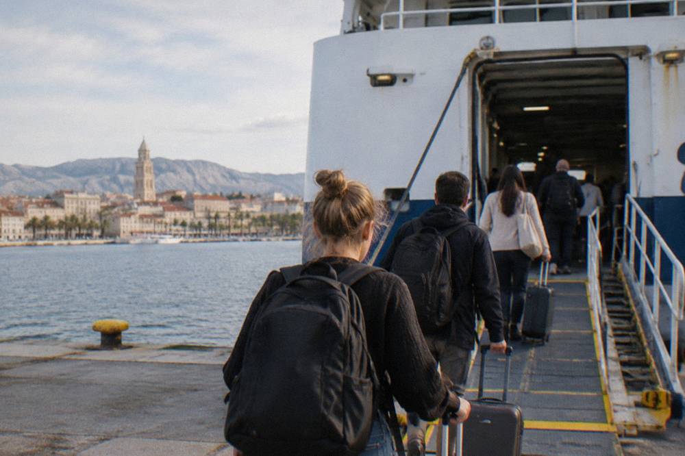 Passengers with bags walking up the gangway of a ferry at a Croatian port