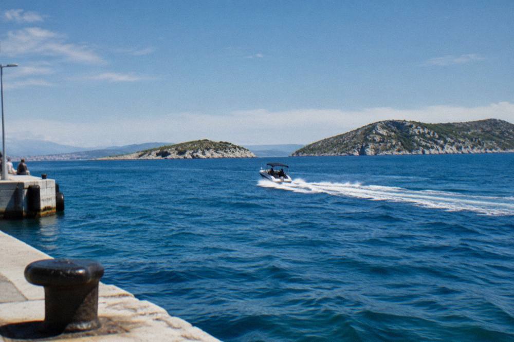 A speedboat cutting across open blue sea toward rocky islands