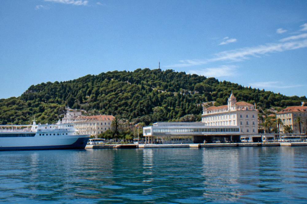 The Split ferry port seen from the water with the forested Marjan hill rising behind the terminal buildings