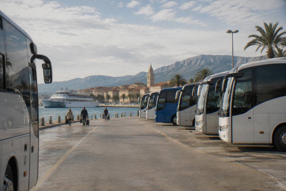 Rows of intercity buses parked at a waterfront bus station beside a ferry port