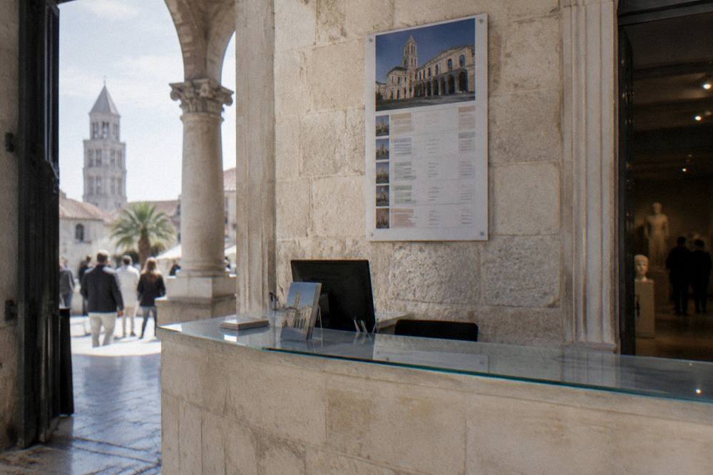 Museum entrance desk with a printed price list on a stone wall