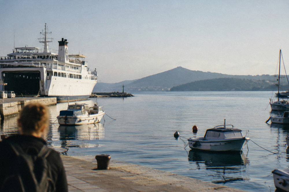 A ferry and small boats moored in a harbour with island hills across the water