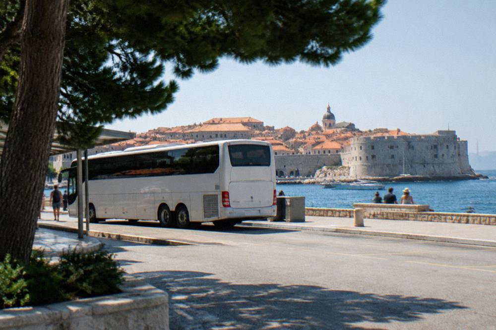 A long distance coach parked at a station platform beside the sea