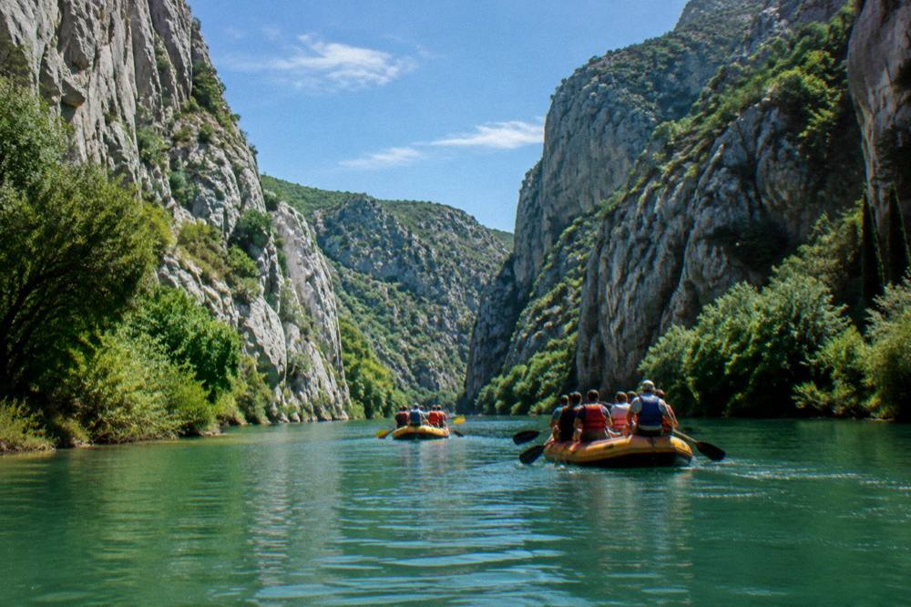 Rafts on a green river between steep rocky canyon walls