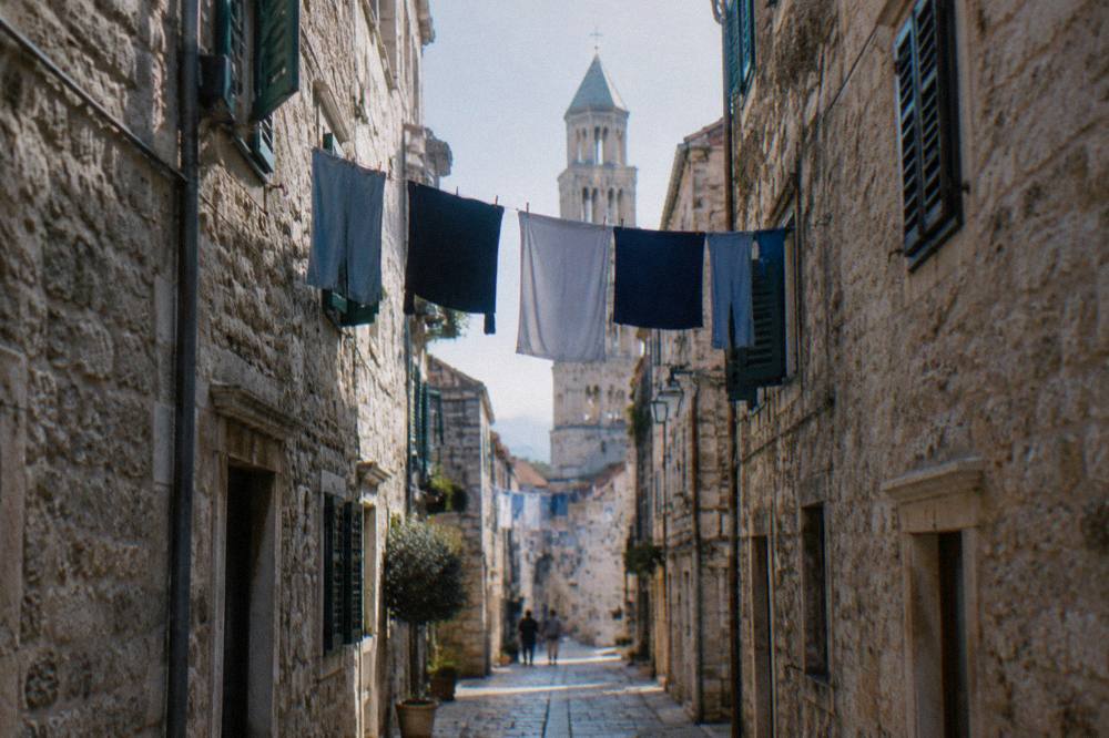 A stone old town street with laundry hanging between buildings