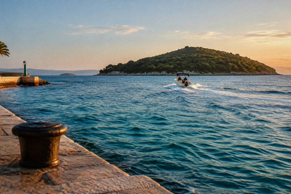 A small speedboat crossing clear turquoise water towards a pine covered Dalmatian island