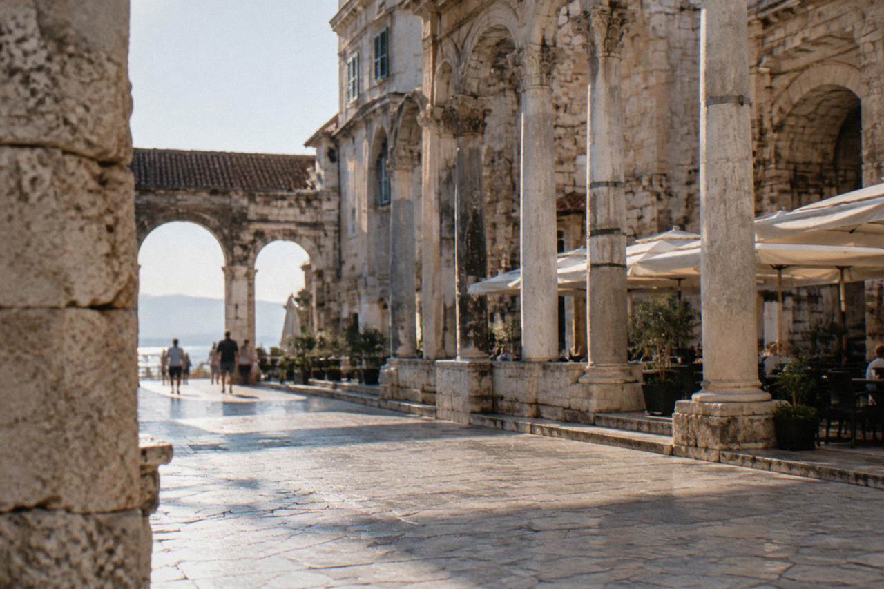 Sunlit stone square of Diocletian's Palace in Split with columns and cafe terraces