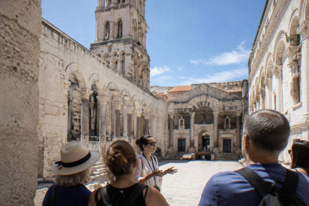 Guide speaking to a small group of visitors in a stone courtyard in Split