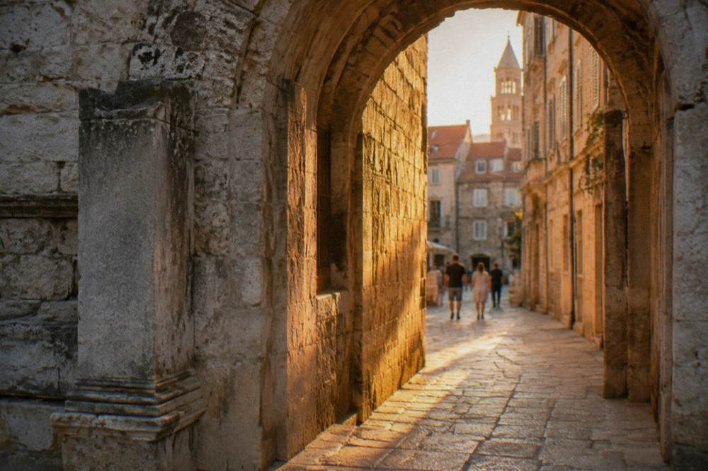 Stone archway leading into a sunlit alley of Split Old Town