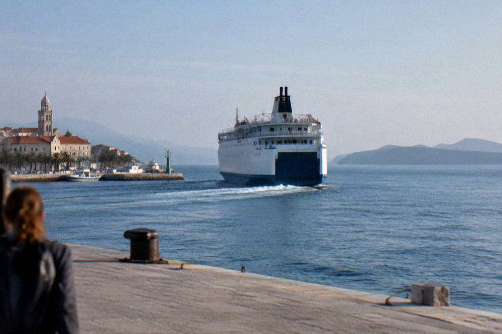 A large ferry leaving Split harbour in bright weather with islands on the horizon