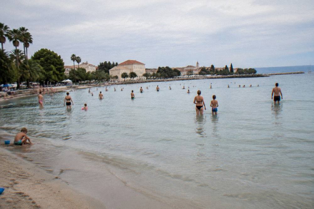 Families swimming in the shallow sandy bay at Bacvice beach in Split