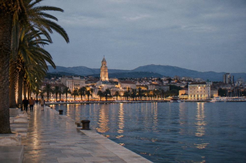 Night skyline of Split with warm lights along the waterfront and hills behind