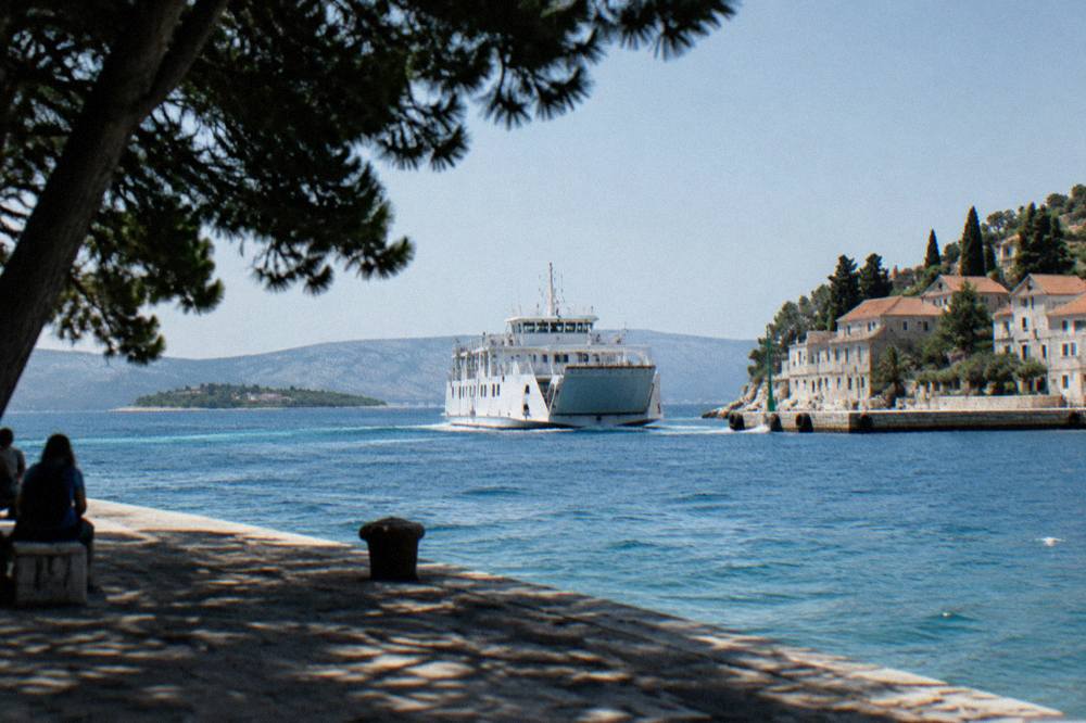 White ferry approaching a stone quay on a Dalmatian island in bright summer light