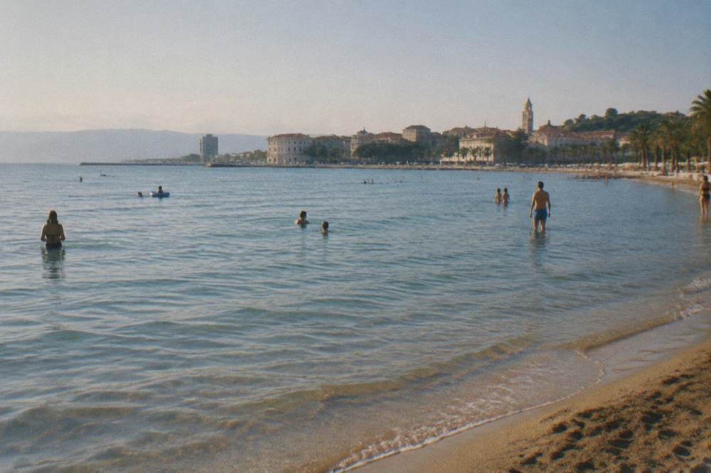 Sandy beach with shallow water and people swimming at Bačvice in Split
