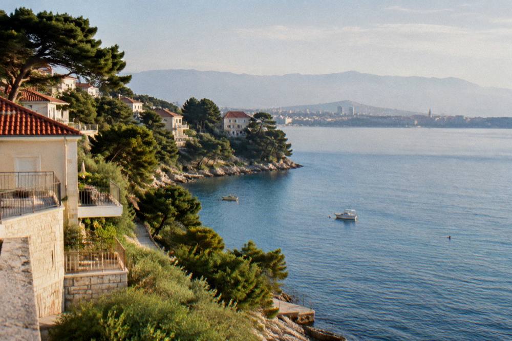 Apartments and pine trees above a calm blue bay on the Split coastline