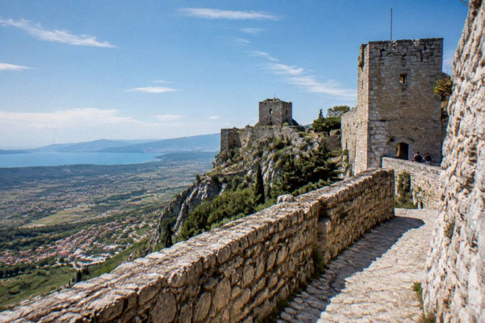 The stone walls and towers of Klis Fortress on a ridge above the surrounding countryside