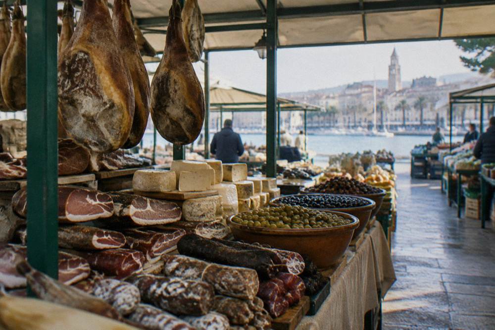 Covered market stall with cured ham, cheese and olives in Split