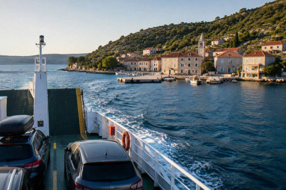 Car ferry approaching a small Dalmatian island harbour with stone houses