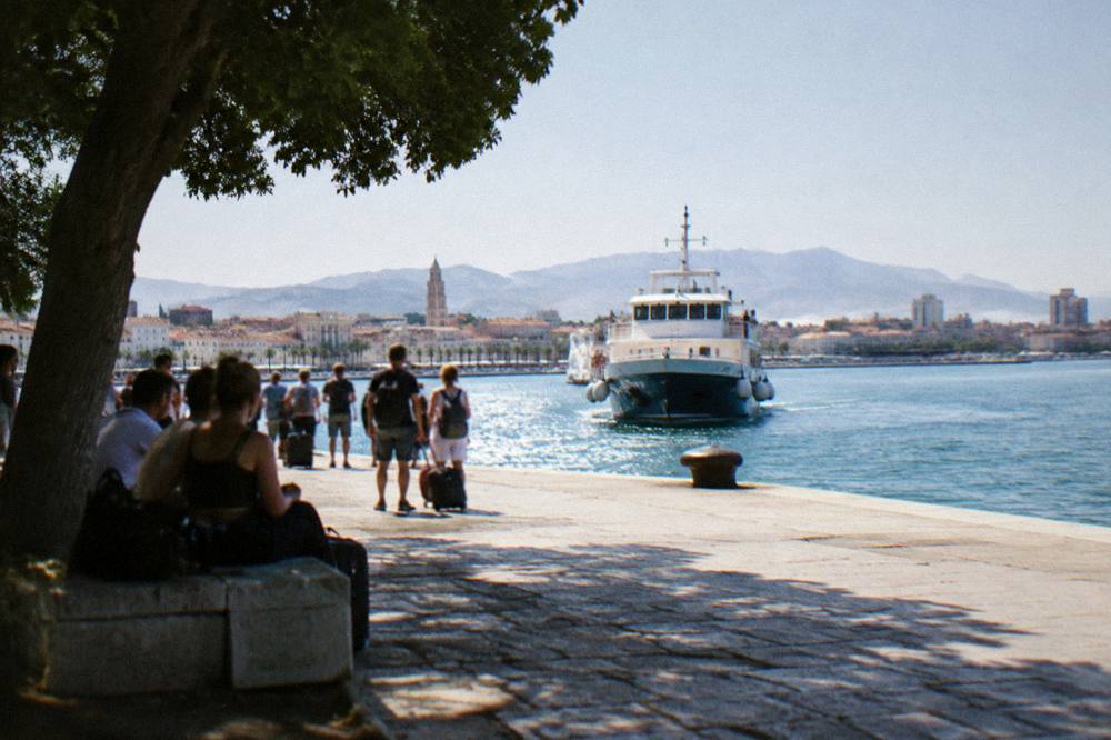 Passengers waiting at an island ferry jetty in late afternoon sun