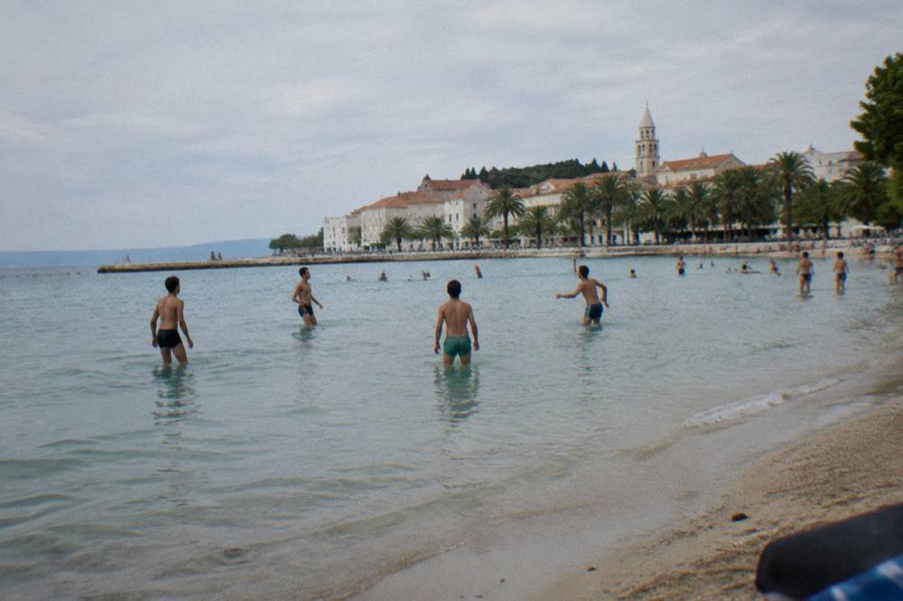 Sandy Bačvice beach in Split with shallow clear water and people playing picigin near the shore