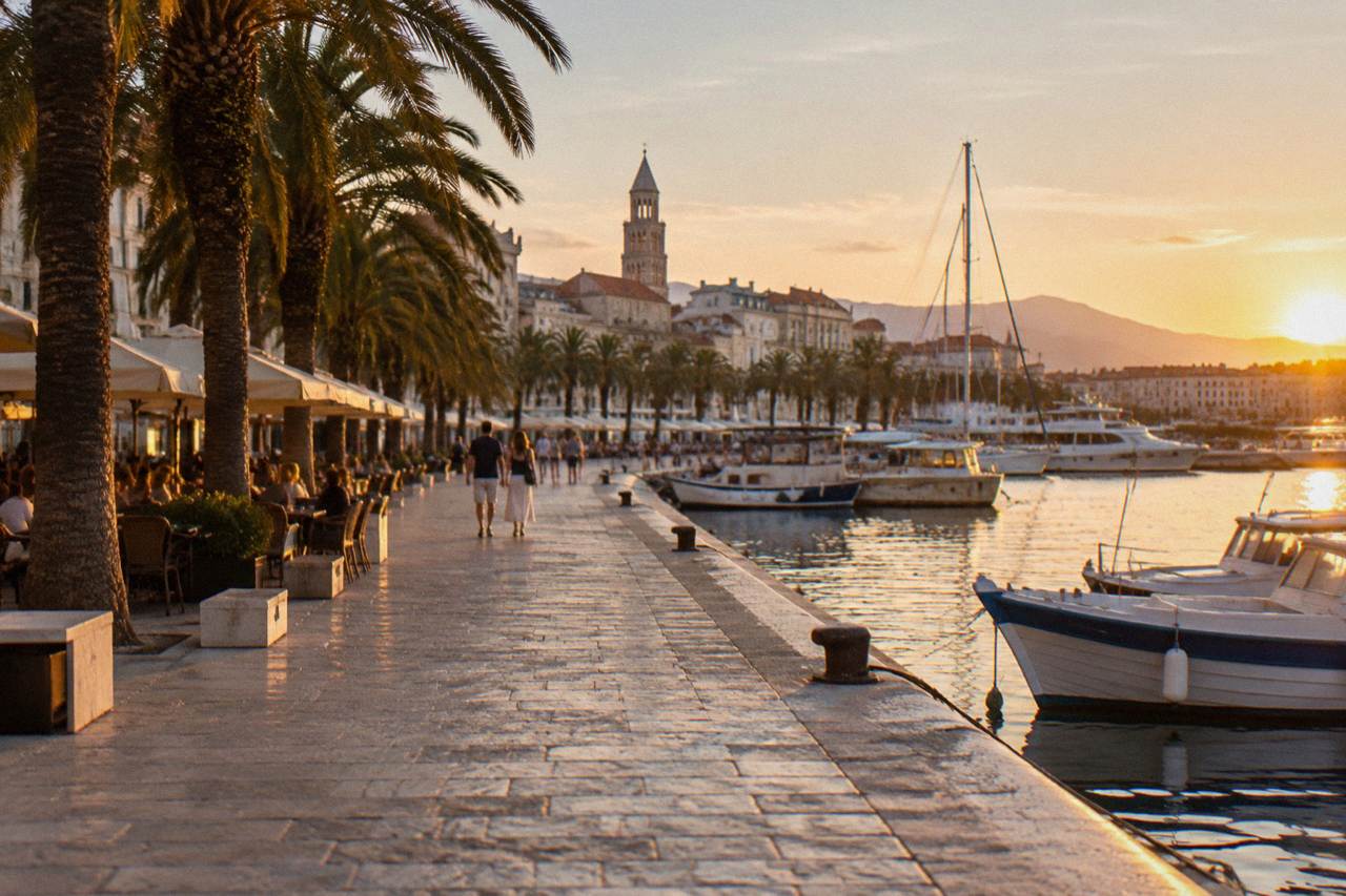 The seafront promenade in Split with palm trees, cafe terraces and moored boats along the Adriatic