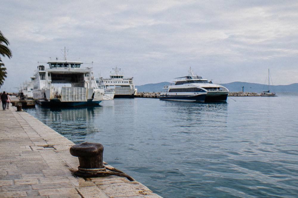 Ferry boats and catamarans moored at the Split waterfront with islands on the horizon